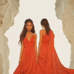 two women in dresses walking down the runway