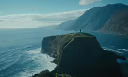 a person standing on top of a cliff over the ocean