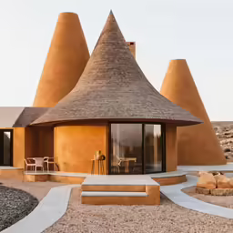 the house features a thatch roof and concrete staircase