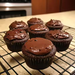 chocolate cupcakes cooling on a wire rack in front of an oven