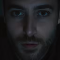 a man in the dark stares ahead with glowing blue eyes