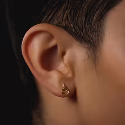 a female wearing earring with small gold circles