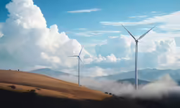 wind turbines on top of a hill next to a clouds filled sky