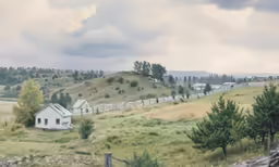 white barn sitting on a farm with green mountains in the background