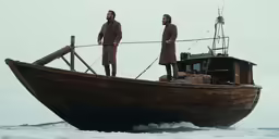 two men dressed in brown standing on the side of a boat