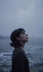 a girl looking up into the sky by the ocean
