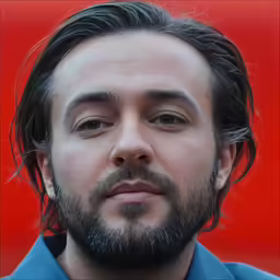 a man with long hair and beard standing by a red wall