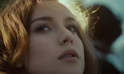 a close - up shot of a young woman with long hair, looking at the camera