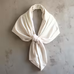 the white knotted scarf is hanging on a wall