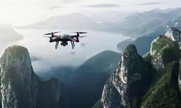 a black and white small helicopter flying over mountains