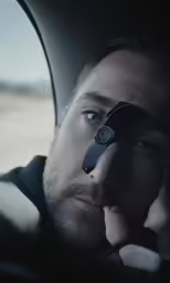 a man in the car looking through the window with a magnifying glass on his eye