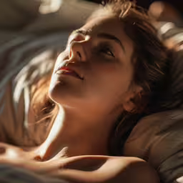 a woman laying in bed with her eyes closed,a beautiful woman laying in bed with a blanket