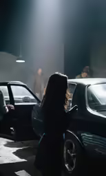 woman in dark coat standing next to two parked cars