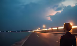 a person standing on a road next to a body of water