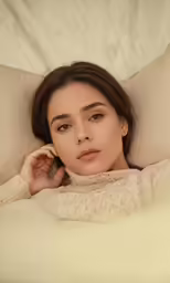 a beautiful young woman laying in bed under a blanket