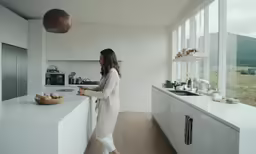 a woman wearing white is looking out the window