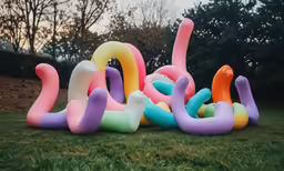 a large number of colorful balloons lay in the grass