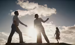 three people standing on top of a rock together