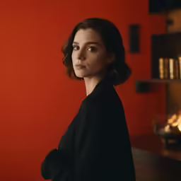 a woman is leaning against a red wall