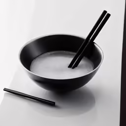 two chopsticks sticking out of an empty bowl