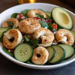 a salad with bagels in a bowl, spinach and tomatoes