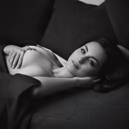 a woman laying on a couch in black and white