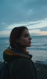 a woman standing on the beach while looking at the water
