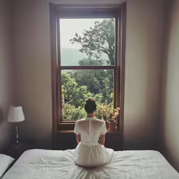a woman in white dress sitting on a bed