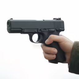 hand holding a gun that is pointed towards the camera