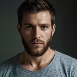 a man wearing a gray shirt poses for a portrait