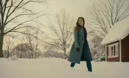 a young woman walking in the snow outside her cabin