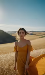 a young woman in a long yellow dress is standing in a field