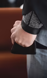 the man is holding a black clutch bag