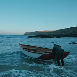 a man is standing in the water near a boat