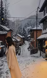 a person with a coat walking along side buildings in snow