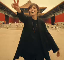 a woman posing with a peace sign by a building