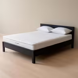 a bed sitting in the middle of a room with a pillow on top