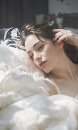 a woman laying in bed while covering her face with a blanket