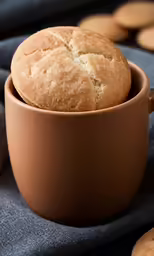 baked bread in a clay mug on top of blue cloth