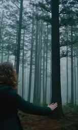 woman walking through dark forest area in fog