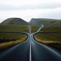 a road passes between two mountains that are both curve in the opposite direction