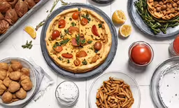 an assortment of food including pizza and baked goods,various types of food and plates sitting on a table