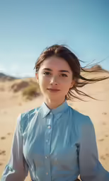 a woman in blue shirt standing on top of a sandy beach