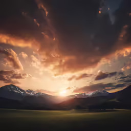 a field in front of some mountains with a setting sun behind them