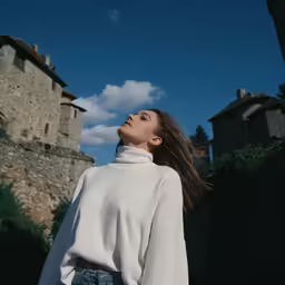 a woman wearing jeans and a sweater looking up