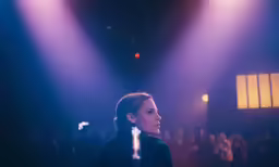 a female singer in front of an audience with blue lights