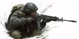 a soldier crouching while holding a machine gun in the snow