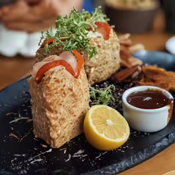 a black plate topped with food and sauce