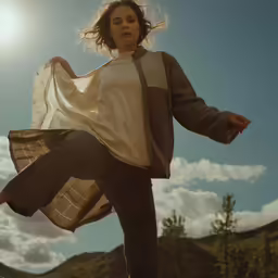 a woman standing in the sky with her hands in her hair