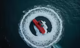 a small red vehicle is driving through an object with many frothers on it